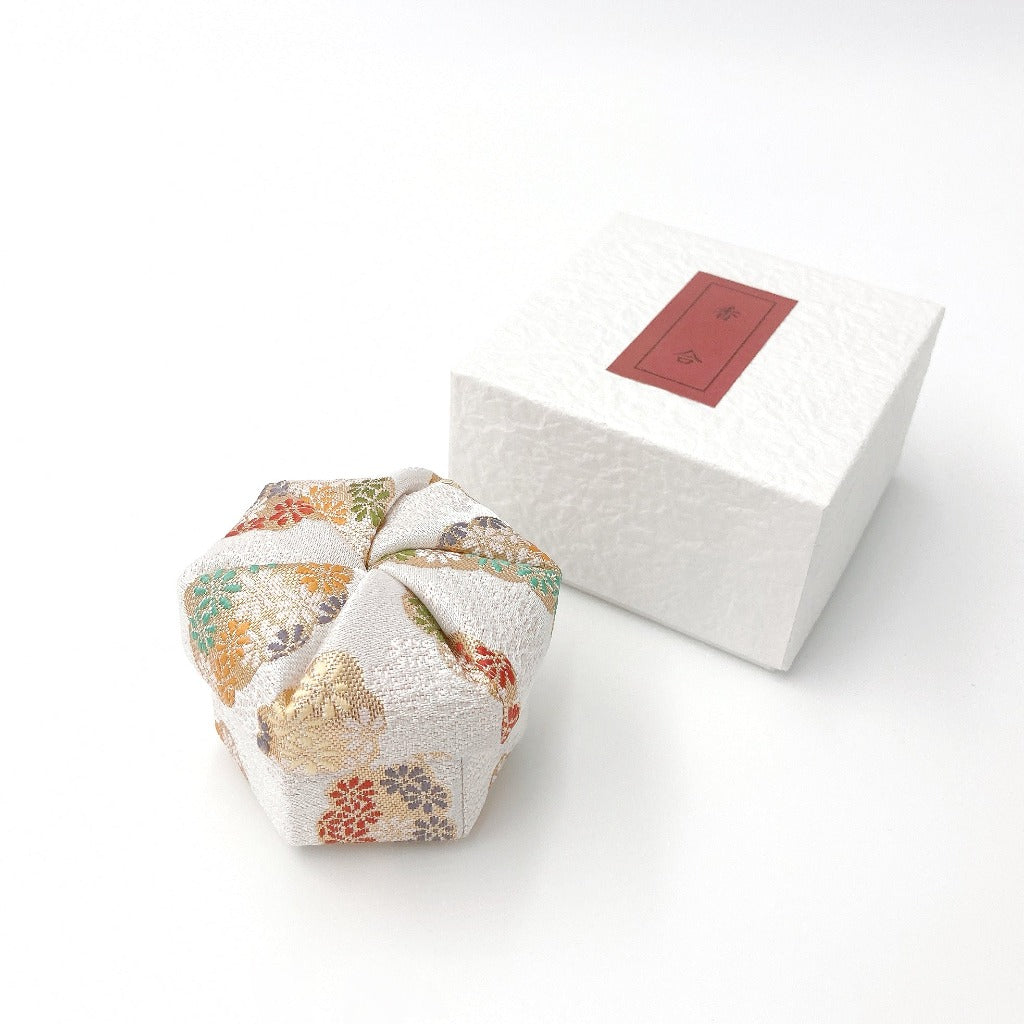 top down angled view of white Nuno-Kougou cloth covered traditional Japanese jewelry box with colorful pattern alongside its box