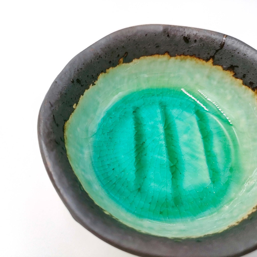 close up of  Maruchiyoku Mamezara with green crackle glaze design on interior surface 