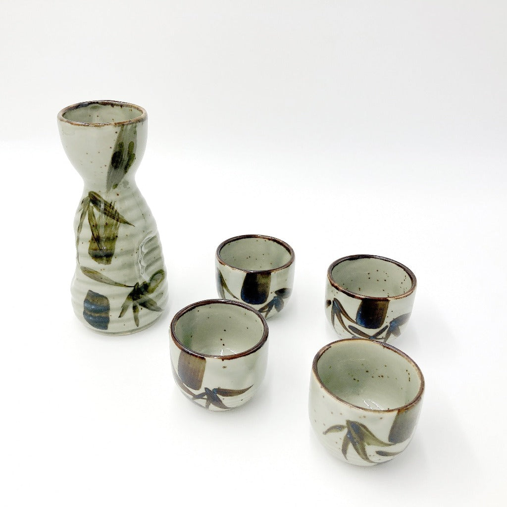 Top down angled view of Mashikotake Sake Set showing the ceramic decanter and four sake cups all with bamboo motifs