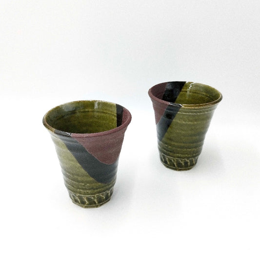 top down angled view of set of two green and brown ceramic Oribe Mugs