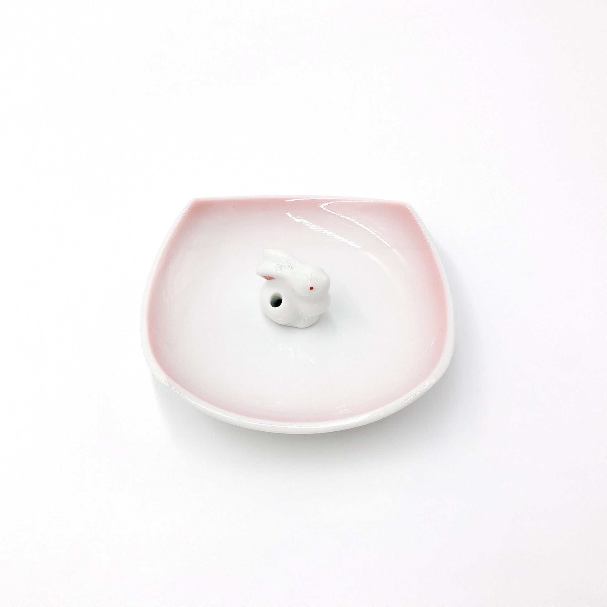 angled view of pink and white ceramic Kyūkyodō Incense Set showing square incense plate and bunny incense stick holder