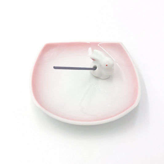 close up angled view of pink and white ceramic Kyūkyodō Incense Set showing square incense plate and bunny incense stick holder