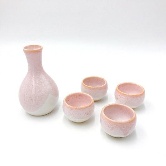 Sakura Sake Set. View of pink sakura themed sake decanter with delicate pink and white pattern and four matching cups.
